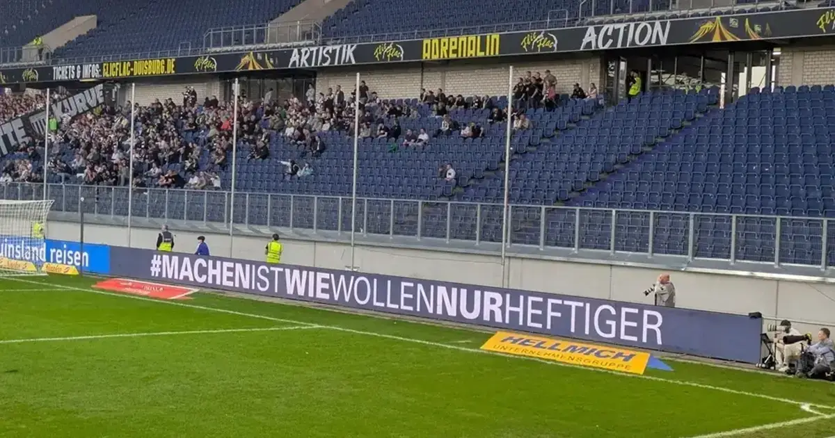 LED-Werbebande mit dem Schriftzug „#MACHENISTWIEWOLLENNURHEFTIGER“ im Stadion unterhalb einer fast leeren Tribüne.
